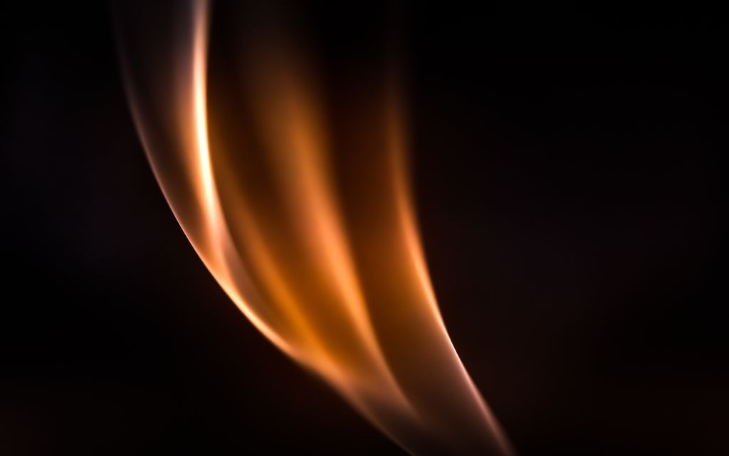 Abstract close-up of a glowing flame against a dark background, capturing elegant motion.